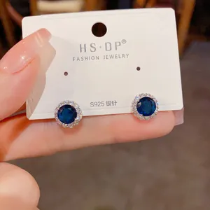 Détail de boucles d'oreilles saphir rondes avec halo de zircon sur carte S925 argent
