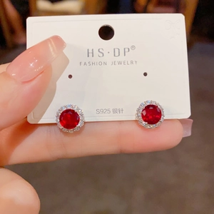 Détail macro de boucles d'oreilles rondes en zircon rouge avec tiges en argent S925