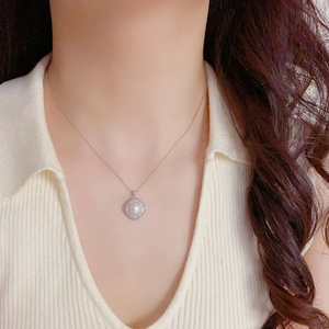 Close-up of elegant micro-set zircon and pearl rhombus pendant on a silver chain