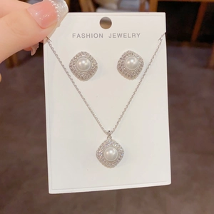 Detailed view of pavé zircon and pearl square jewelry set with necklace and earrings