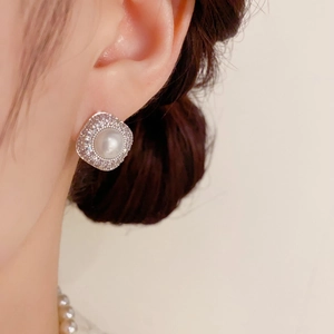 Macro shot of elegant square pearl earring with micro-paved cubic zirconia on model ear