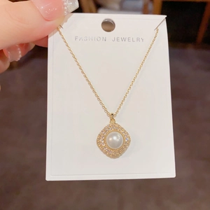 Macro shot of gold-tone necklace with a central pearl and pave zirconia in a diamond shape
