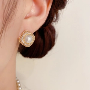 Detailed view of luxury square pearl earrings with micro-set zircons on a model