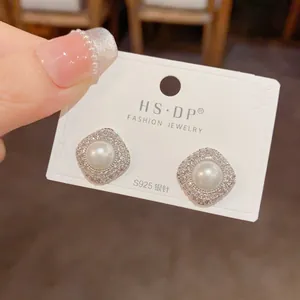 Close-up of S925 silver needle earrings featuring micro-pave zircons and white pearls