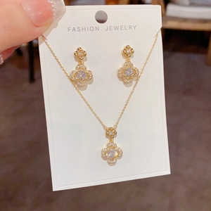 Detailed close-up of golden four-leaf flower jewelry set with sparkling zircon crystals