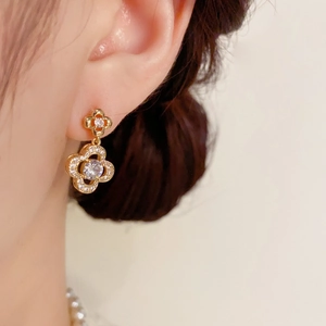 Detail shot of gold four-leaf clover earrings with micro-pave cubic zirconia on a model