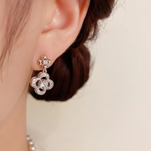 Close-up of elegant four-leaf flower earrings with micro-set cubic zirconia on a model