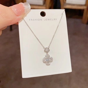 Detailed macro of a silver clover necklace with shimmering zircon pavé and fine cross chain