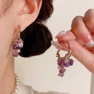Detail of purple stone and pearl grape cluster drop earrings on gold hooks