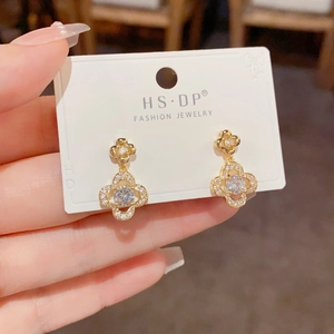 Detail of gold clover earrings with micro-pave cubic zirconia on brand display card