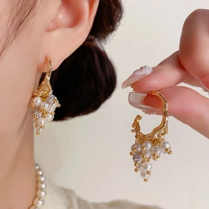 Detail of gold grape cluster earrings with white pearls and sparkling rhinestones