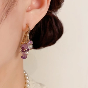 Detailed close-up of grape-shaped beaded earrings with purple crystals and gold hooks