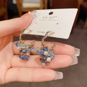 Detail of C-shaped gold ripple earrings with blue crushed stones and white pearls