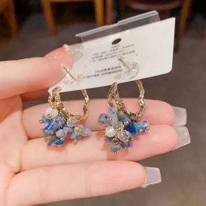 Detail of 14K gold plated C-hoop earring with hanging blue crystals and white pearl