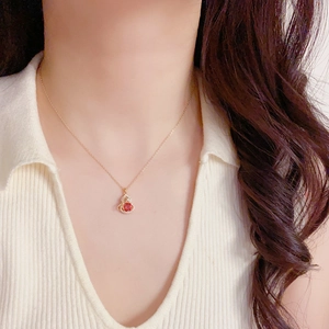 Elegante goldene Halskette mit rotem Zirkon-Kürbis-Anhänger und Schleife an weiblichem Modell