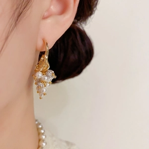 Elegant gold grape cluster earrings with pearls and crystals worn by a model