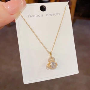 Detailansicht einer goldenen Halskette mit Zirkonia-besetztem Flaschenkürbis-Anhänger