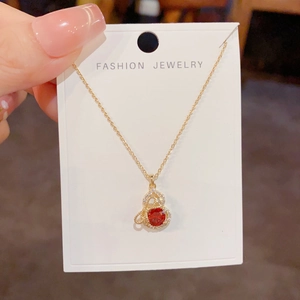 Detail einer Goldkette mit einem Flaschen-Anhänger mit rotem Zirkon und Schleifen-Design