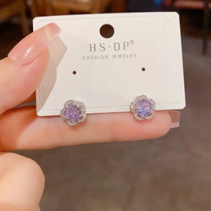 Détail macro d'une boucle d'oreille fleur en argent avec zircon violet et cristaux pavés