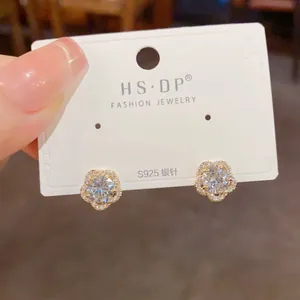 Détail de boucles d'oreilles fleur avec zircone et tiges en argent S925 sur une carte