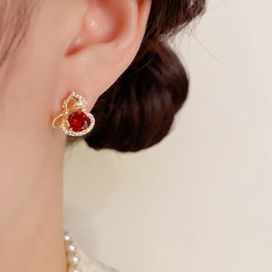 Détail d'une boucle d'oreille en forme de gourde avec gemme rouge et base dorée