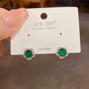 Gros plan détaillé de boucles d'oreilles fleurs en argent S925 et pierres vert émeraude