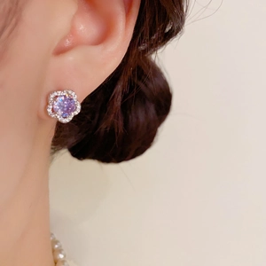 Gros plan d'une boucle d'oreille fleur avec zircon violet et cristaux scintillants