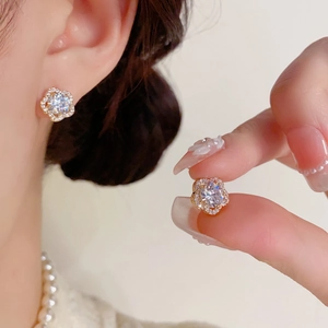 Gros plan de boucles d'oreilles fleur étincelantes avec zircon central et contour doré