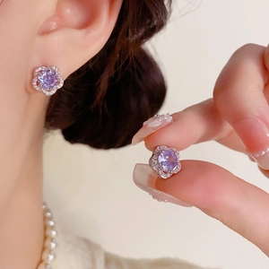 Détail macro des boucles d'oreilles fleur en argent avec zircone cubique violette