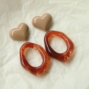 Detail van hars hart oorknopjes en amberkleurige acryl ringen voor DIY sieraden maken
