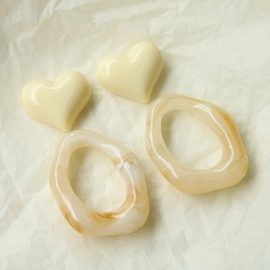 Macro detail van amberkleurige harsring en beige hart hanger voor DIY sieraden maken