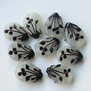 Macro shot of irregular cream glass beads with brown floral patterns for DIY jewelry