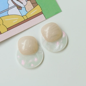 Detailed macro view of minimalist acrylic stud earrings with pearlescent finish and glitter