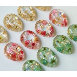 Pendenti a goccia in resina fatti a mano con fiori secchi e foglia d'oro su sfondo bianco