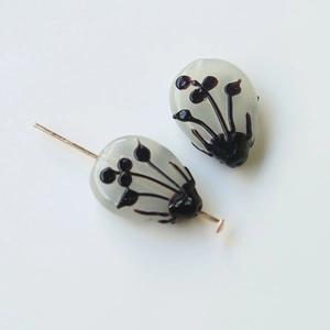 Macro shot of two translucent gray waterdrop glass beads with hand-painted floral patterns