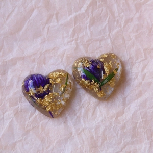 Macro detail of heart resin charms with purple dried flowers and gold foil flakes