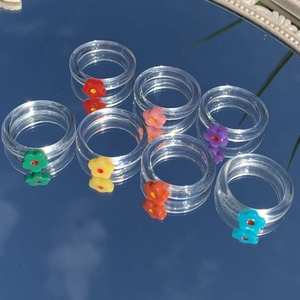 Set mit 7 transparenten Harzringen mit bunten Blumen-Charms auf einer Spiegelfläche