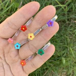 Set mit sieben transparenten Harzringen mit bunten Blumenmustern an der Hand getragen