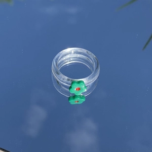Makroaufnahme eines klaren Harzrings mit grüner Blume, der den blauen Himmel reflektiert