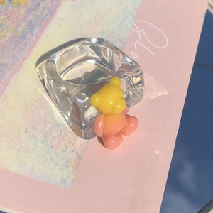Macro detail of a clear acrylic ring featuring a vibrant 3D gradient resin bear pendant