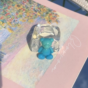 Macro view showing transparent resin square ring with a 3D blue gradient gummy bear detail