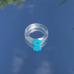 Nahaufnahme eines transparenten Harzrings mit süßem blauen Blumenmuster auf Spiegel