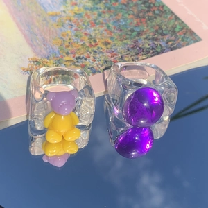 Transparent acrylic bear ring and purple bead statement jewelry on mirror