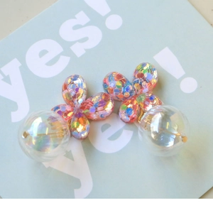 Detalle de aretes florales con lentejuelas de colores y colgante de esfera clara