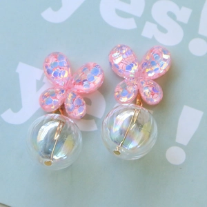 Detalle de pendientes de mariposa en resina con purpurina rosa y cuentas luminiscentes