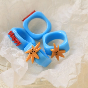 Sky blue resin ring set featuring 3D Happy text and orange smiley star charms