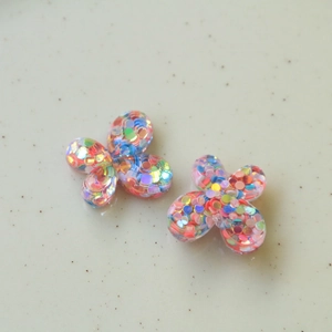 Vista macro de dijes de mariposa de resina con lentejuelas coloridas para joyas DIY