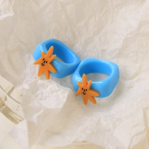 Detail of blue resin rings featuring orange starfish with happy facial expressions