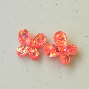 Detalle de dijes de mariposa en resina rosa coral con lentejuelas para manualidades DIY