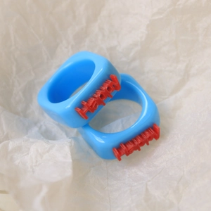 Detail of two light blue Y2K resin rings featuring 3D red Happy lettering on white background
